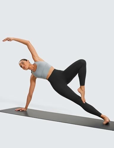 Person practicing yoga side plank pose on mat.